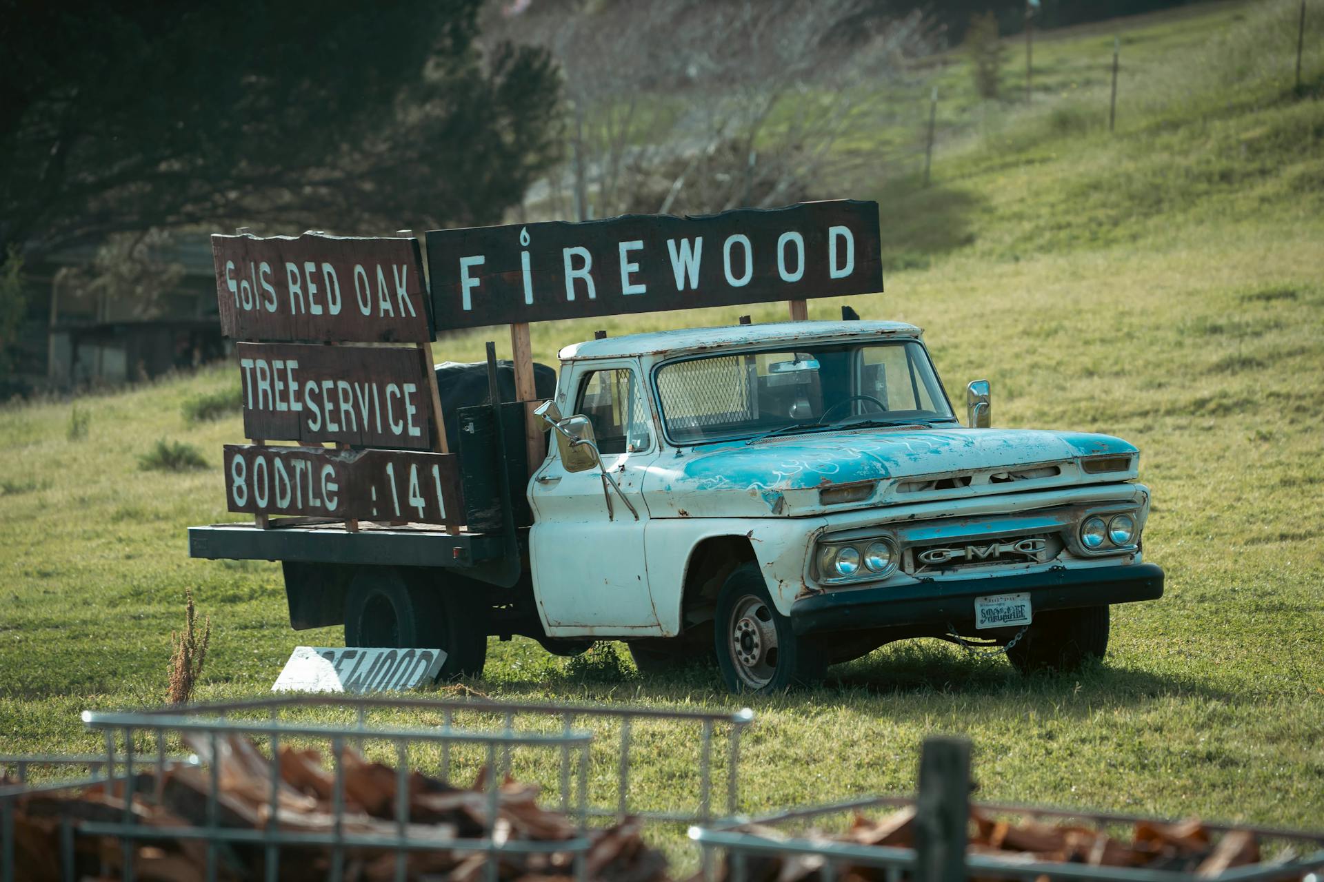 Rustic vintage GMC truck promoting firewood delivery in rural setting.
