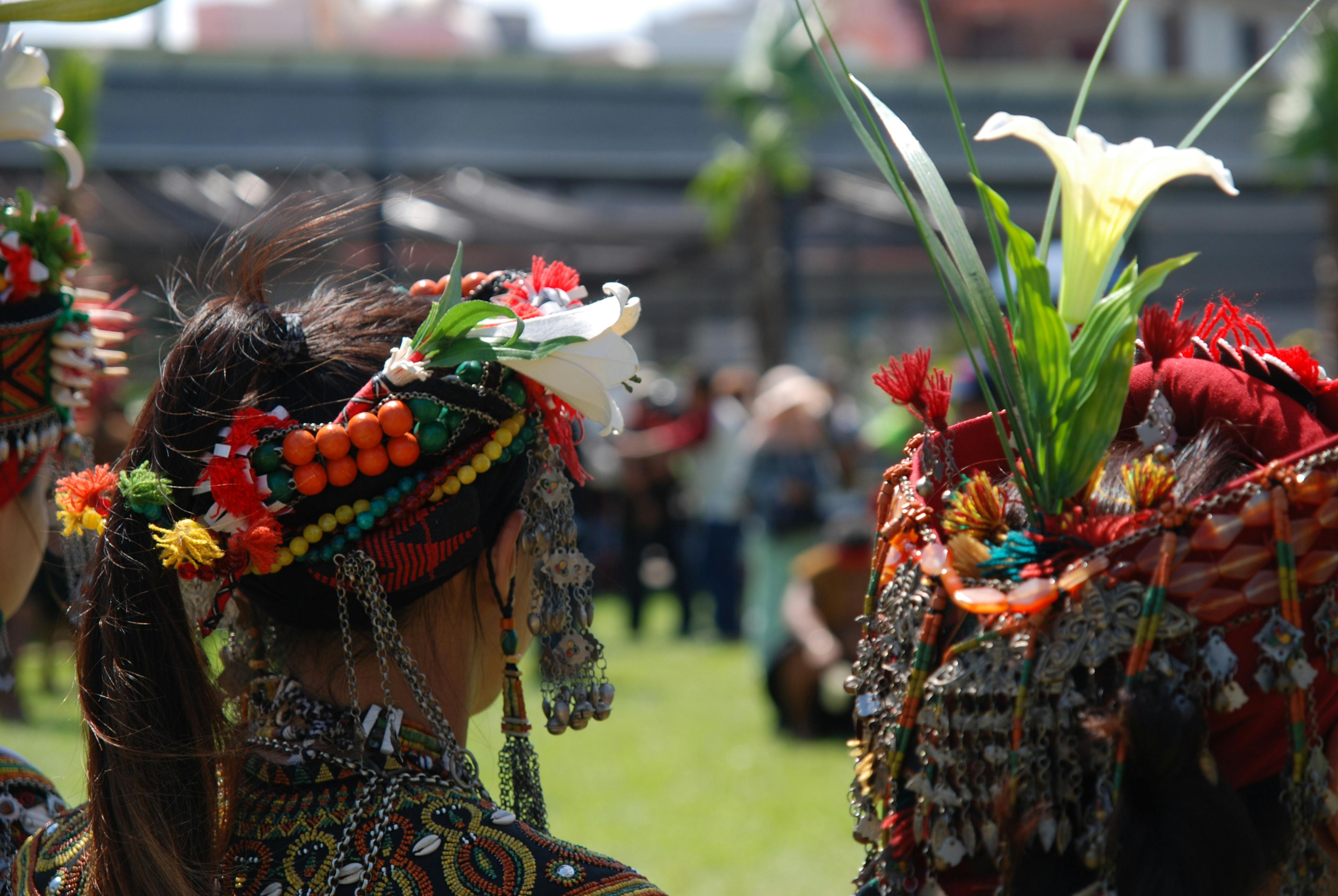 Women in vibrant traditional attire and headdresses at an outdoor cultural festival.