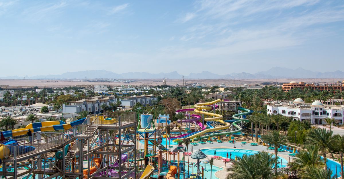 Aerial view of a lively water park with colorful slides and pools on a sunny day, surrounded by dese