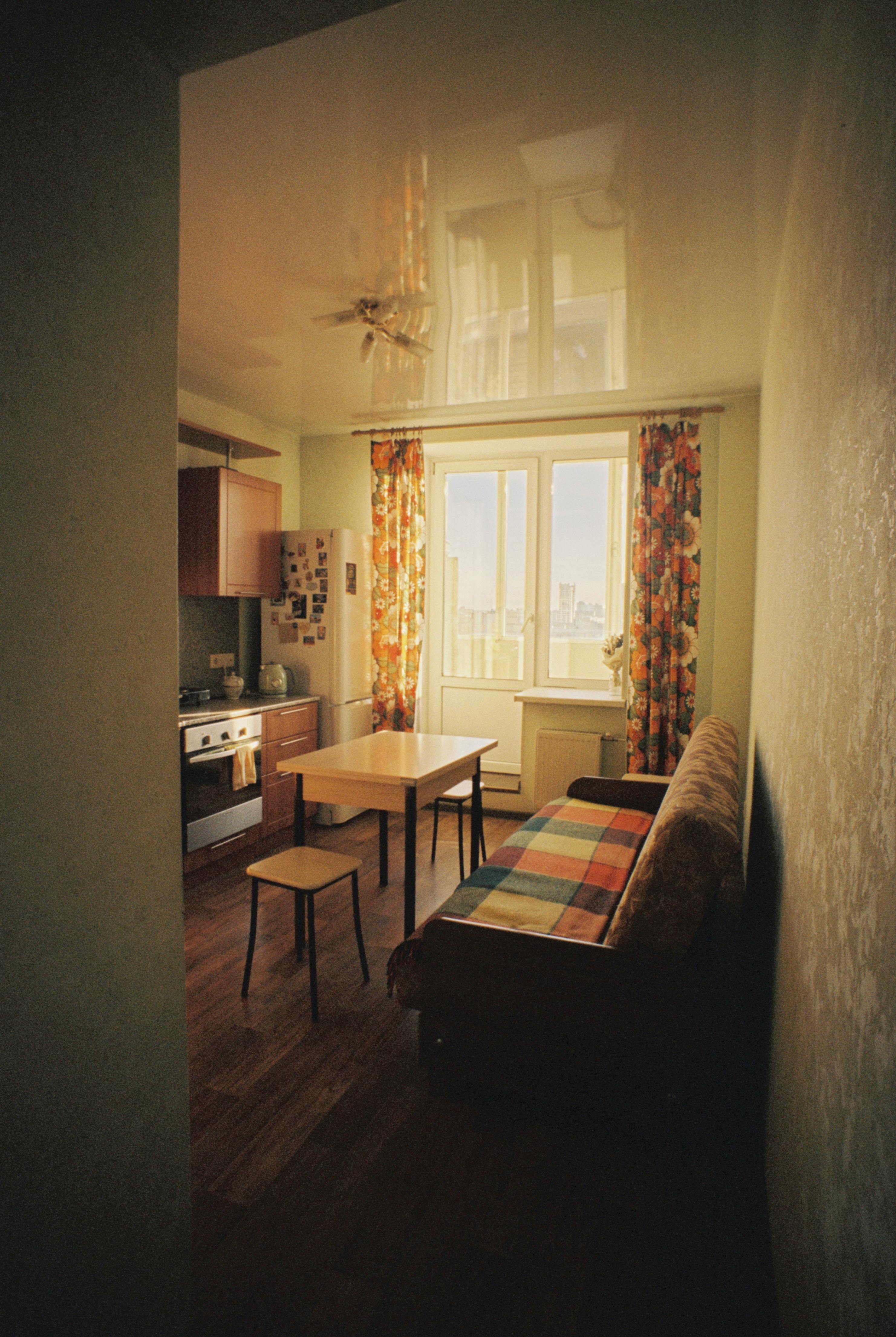 An inviting vintage-style kitchen with floral curtains and retro furnishings bathed in soft daylight.