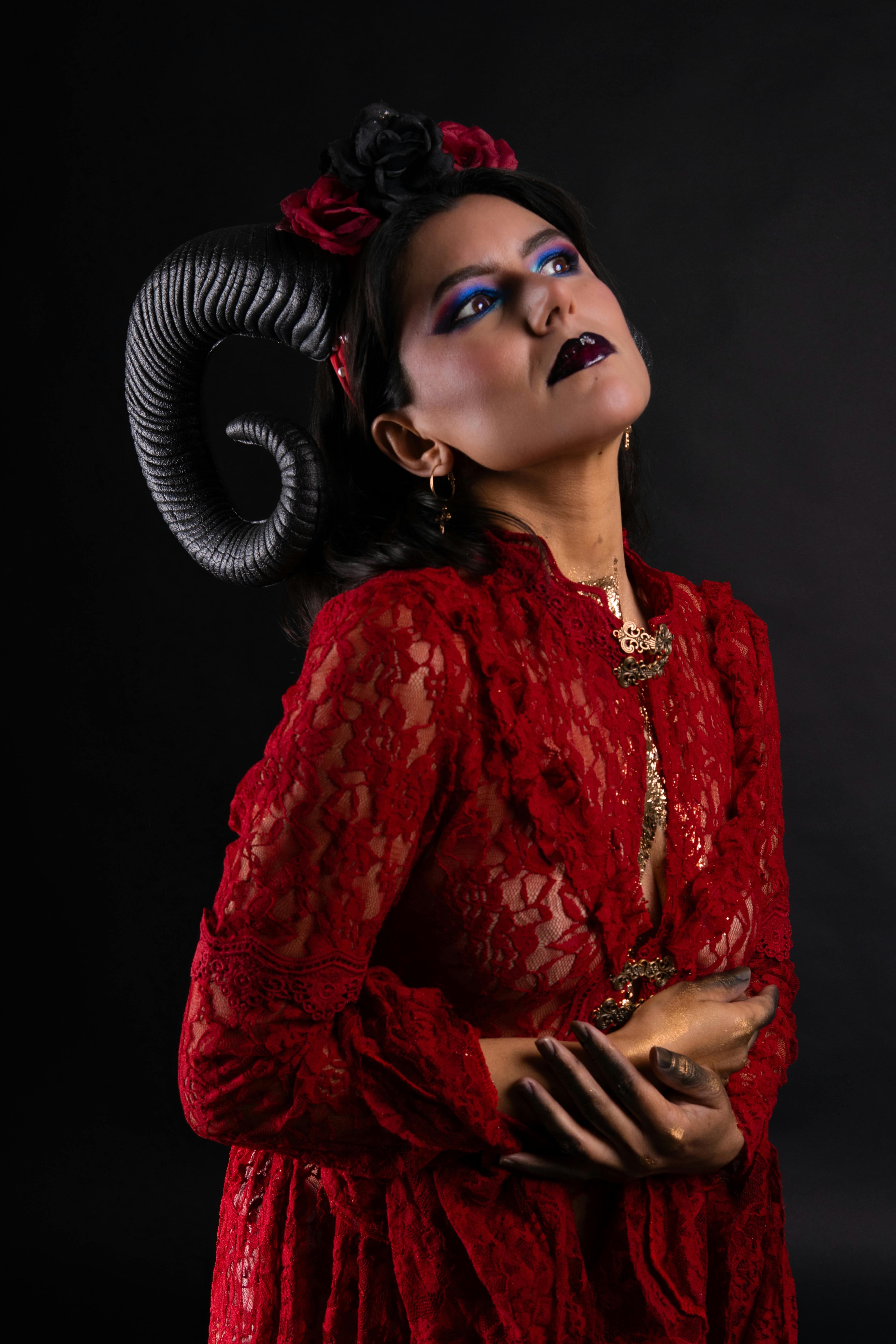 Gratuit Un portrait saisissant d'une femme vêtue d'une robe en dentelle rouge et de cornes sur fond noir. Photos
