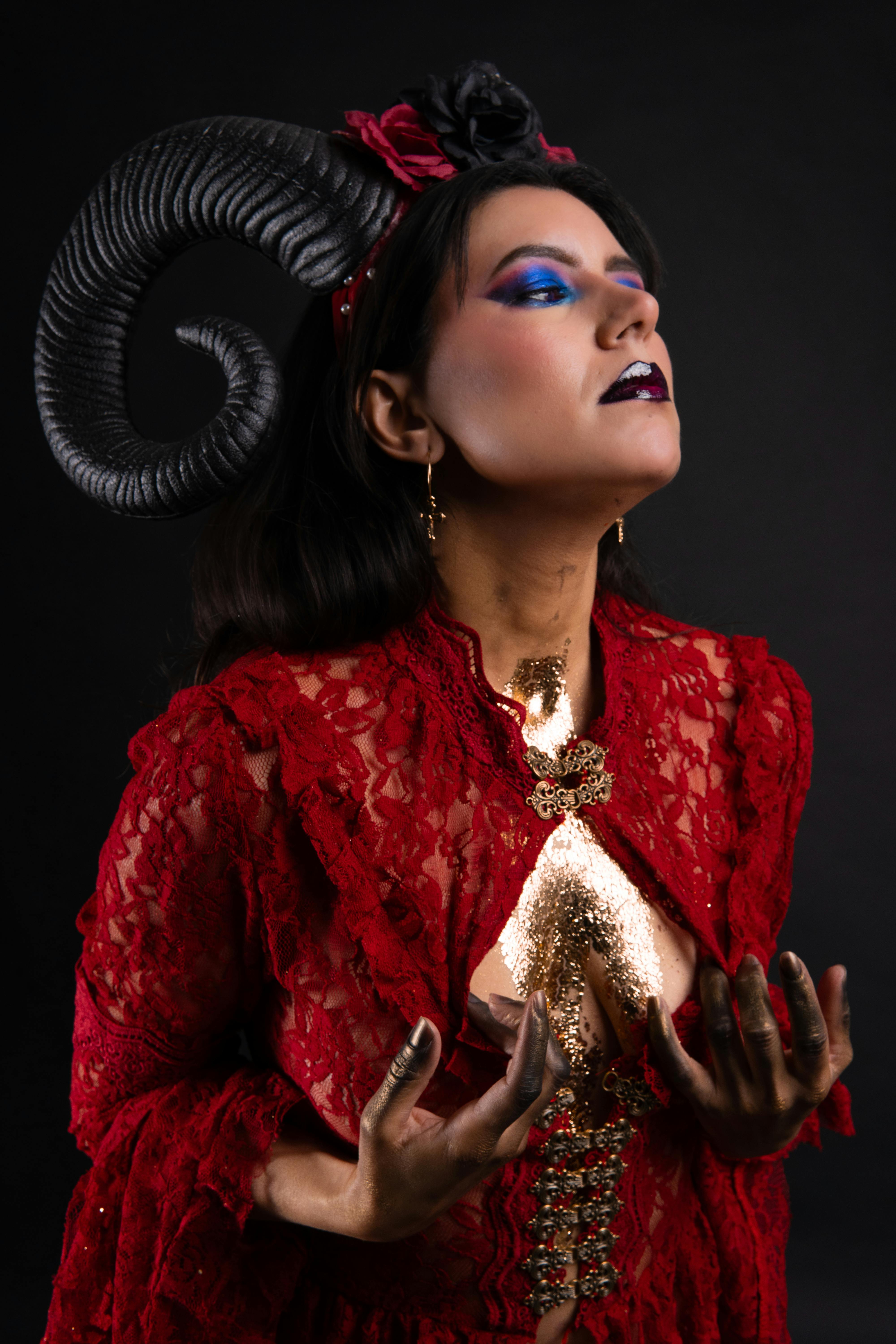 Gratuit Photo de mode éditoriale saisissante d'une femme latine avec des cornes et un maquillage vibrant sur fond noir. Photos