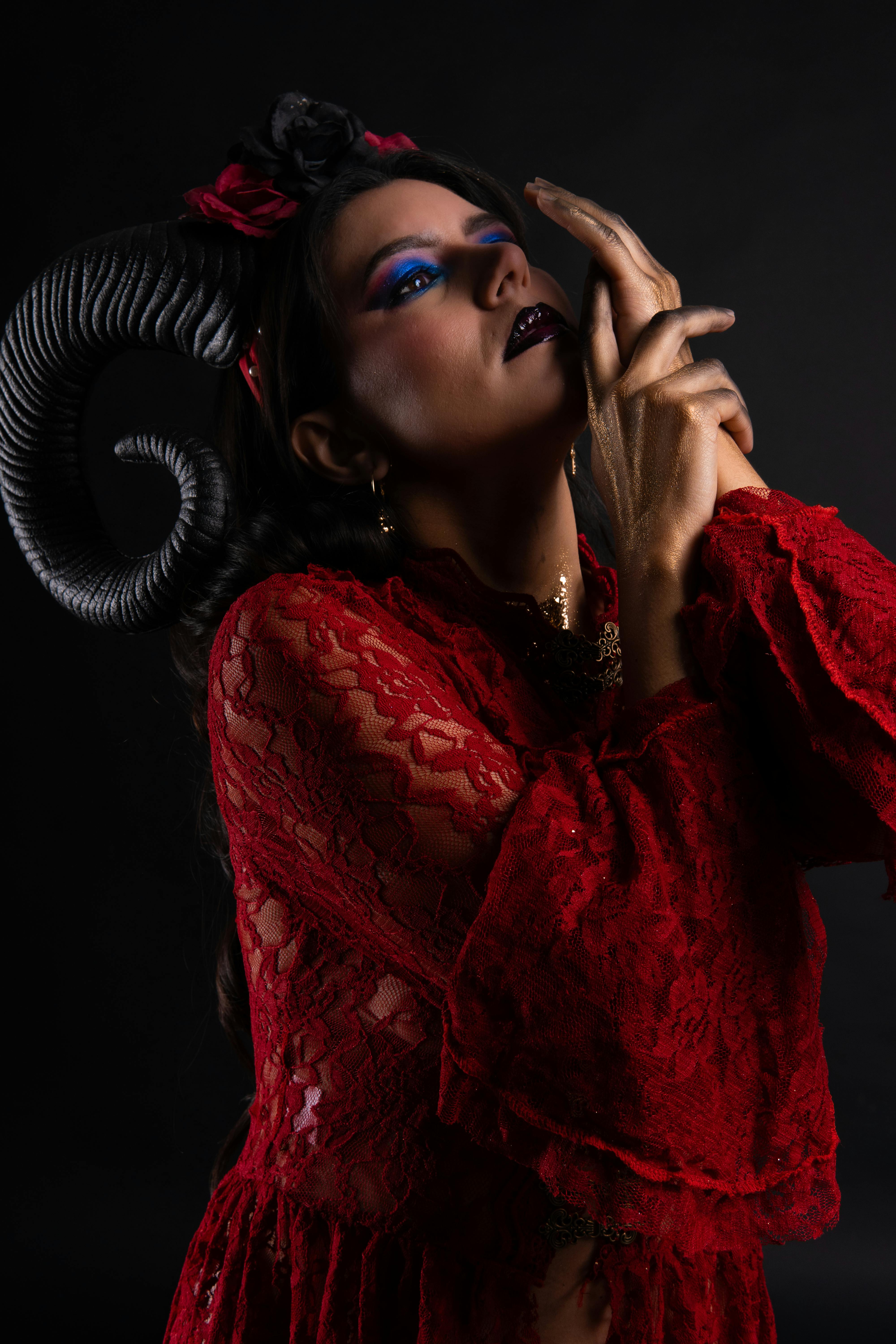 Gratuit Portrait dramatique d'une femme en dentelle rouge avec des cornes, dégageant un attrait mode intense sur un fond sombre. Photos