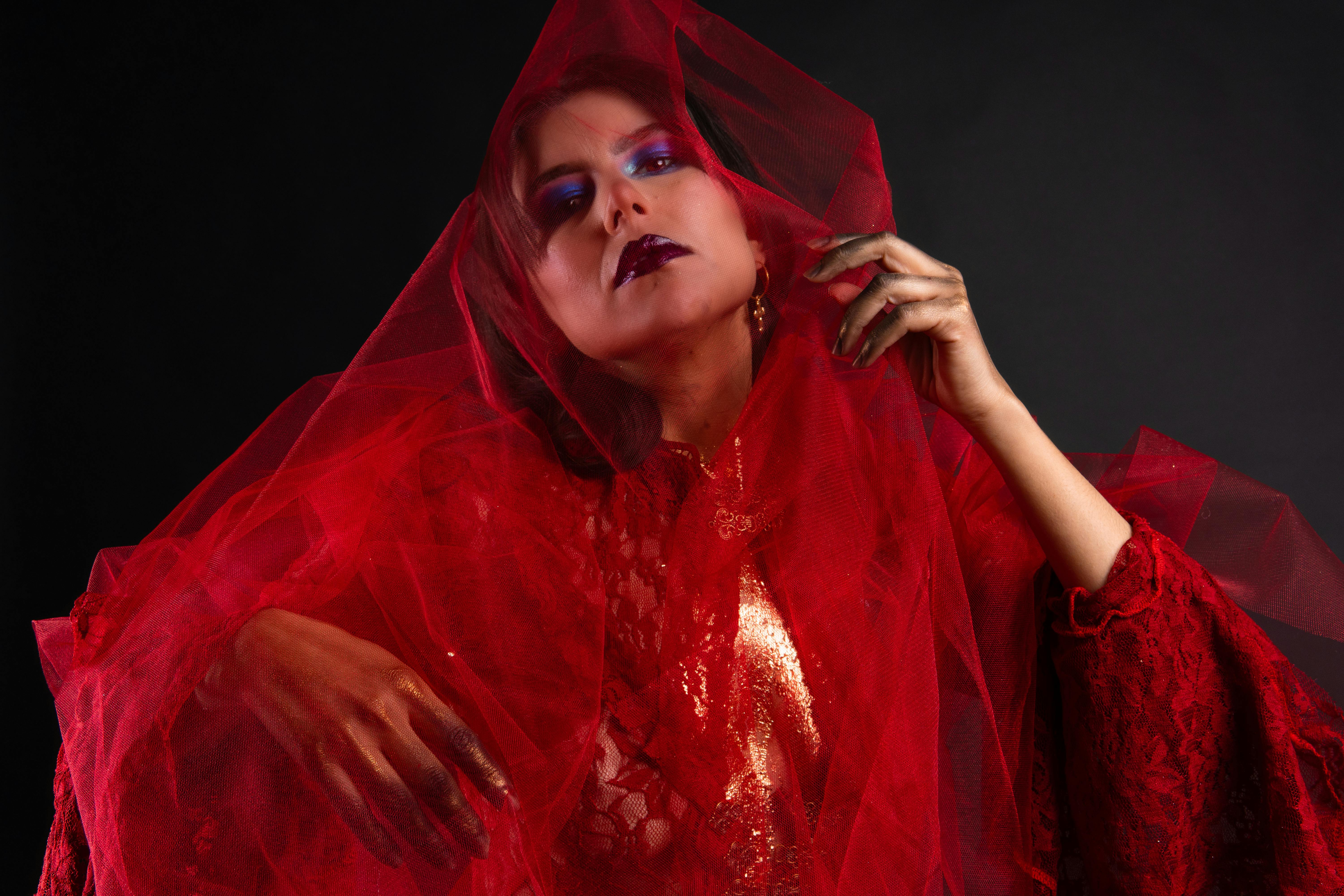 Elegant and bold fashion portrait featuring a model in a red tulle dress and artistic makeup.
