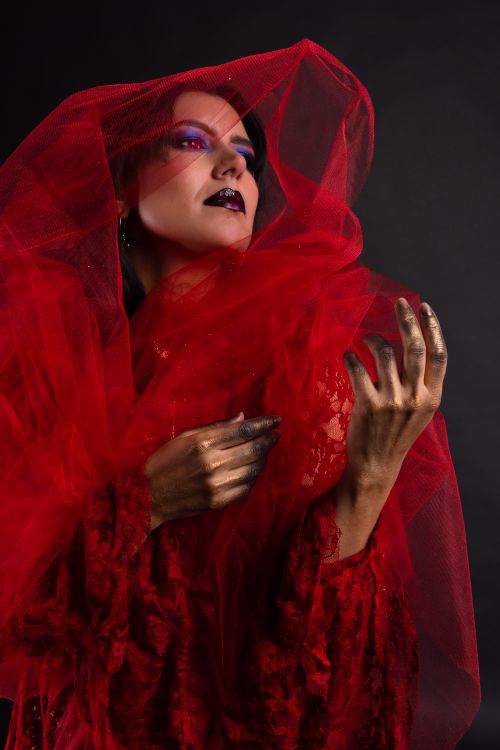 Free Dramatic portrait of a woman in a red tulle dress with golden hands and bold makeup. Editorial fashion look. Stock Photo
