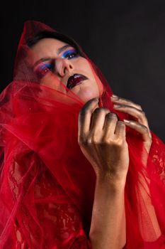 Artistic portrait of a woman in red tulle with golden hands and vibrant makeup.