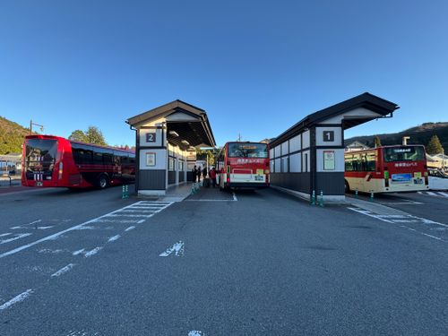 Free Outdoor bus station with multiple buses under a clear sky in a serene location. Stock Photo