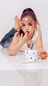 A playful child celebrating a 7th birthday with glitter and cake.