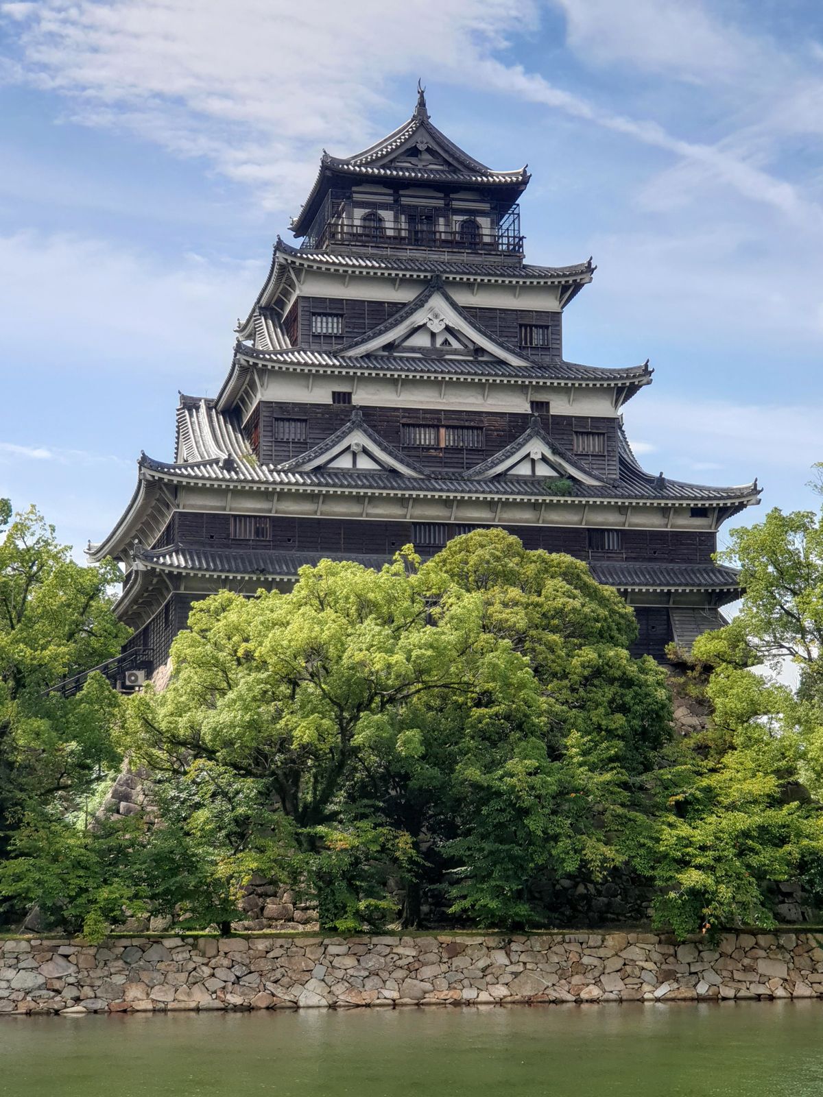 Hiroshima Castle surrounded by green trees under a clear blue sky