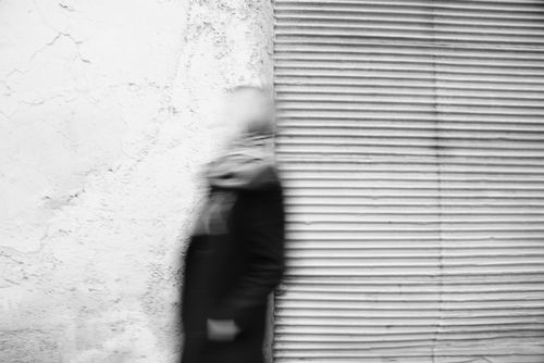 Free Blurred motion of a person walking past a textured urban wall in monochrome. Stock Photo