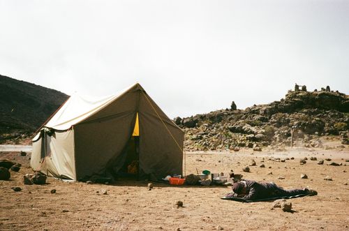 Free Tent setup amidst rocky terrain at Mount Kilimanjaro, Tanzania. Perfect for adventurers. Stock Photo