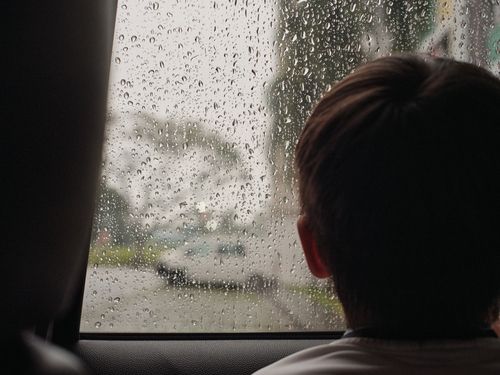 Free A child looking out a rain-soaked car window, capturing a moment of reflection. Stock Photo