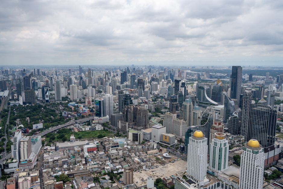 Stunning aerial view of Bangkok's modern skyline under clouded skies.