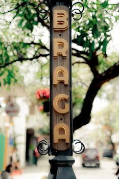 Vertical street sign on Braga Street, surrounded by lush trees in Bandung, Indonesia