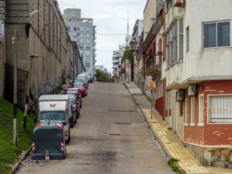 Quiet urban street with parked cars and residential buildings in Montevideo, Uruguay.