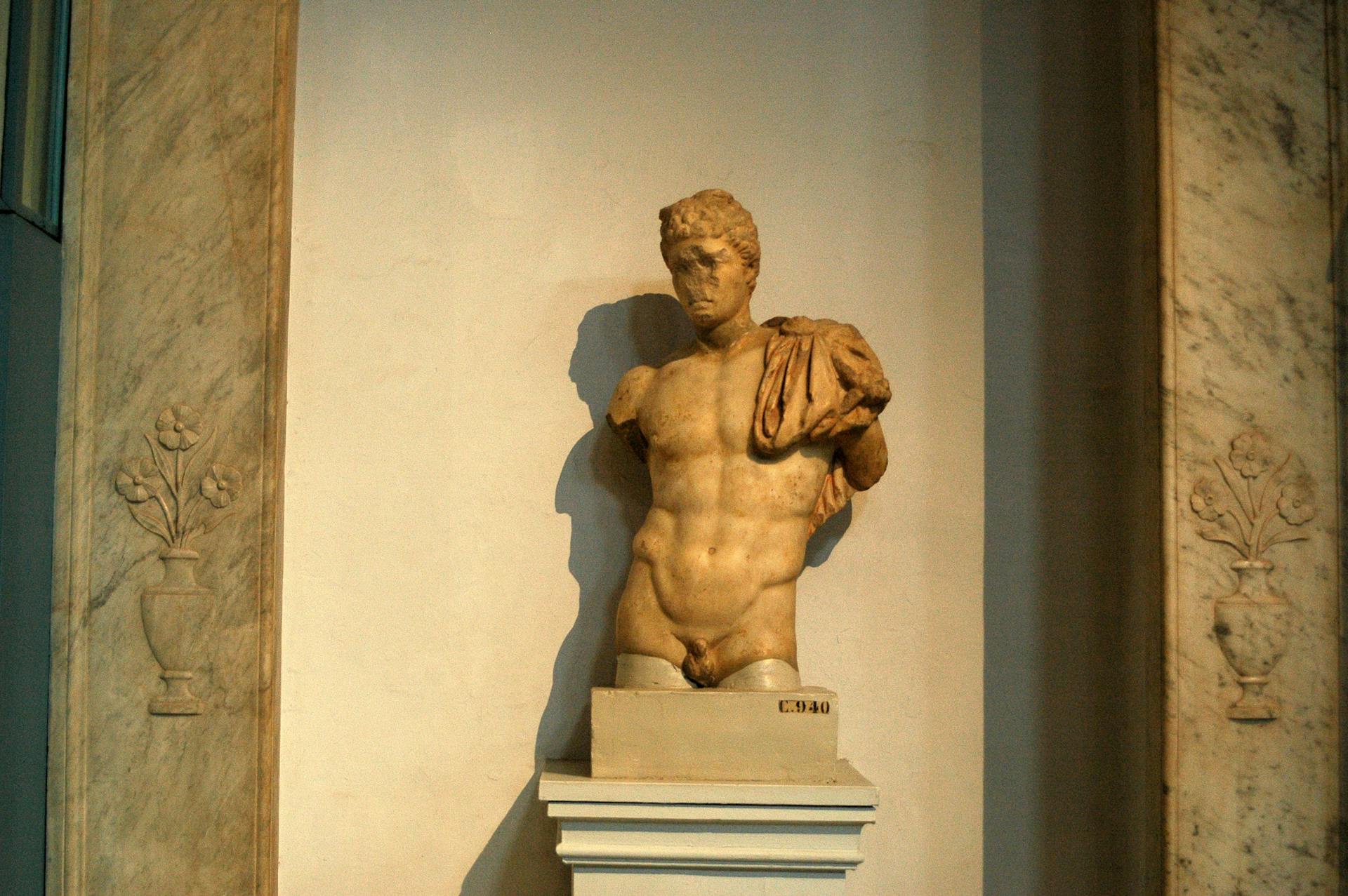 A detailed view of a classical Greek marble statue in a museum setting.