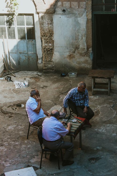 Free Three senior men engaging in a social backgammon game in a rustic courtyard in Istanbul, Turkey. Stock Photo