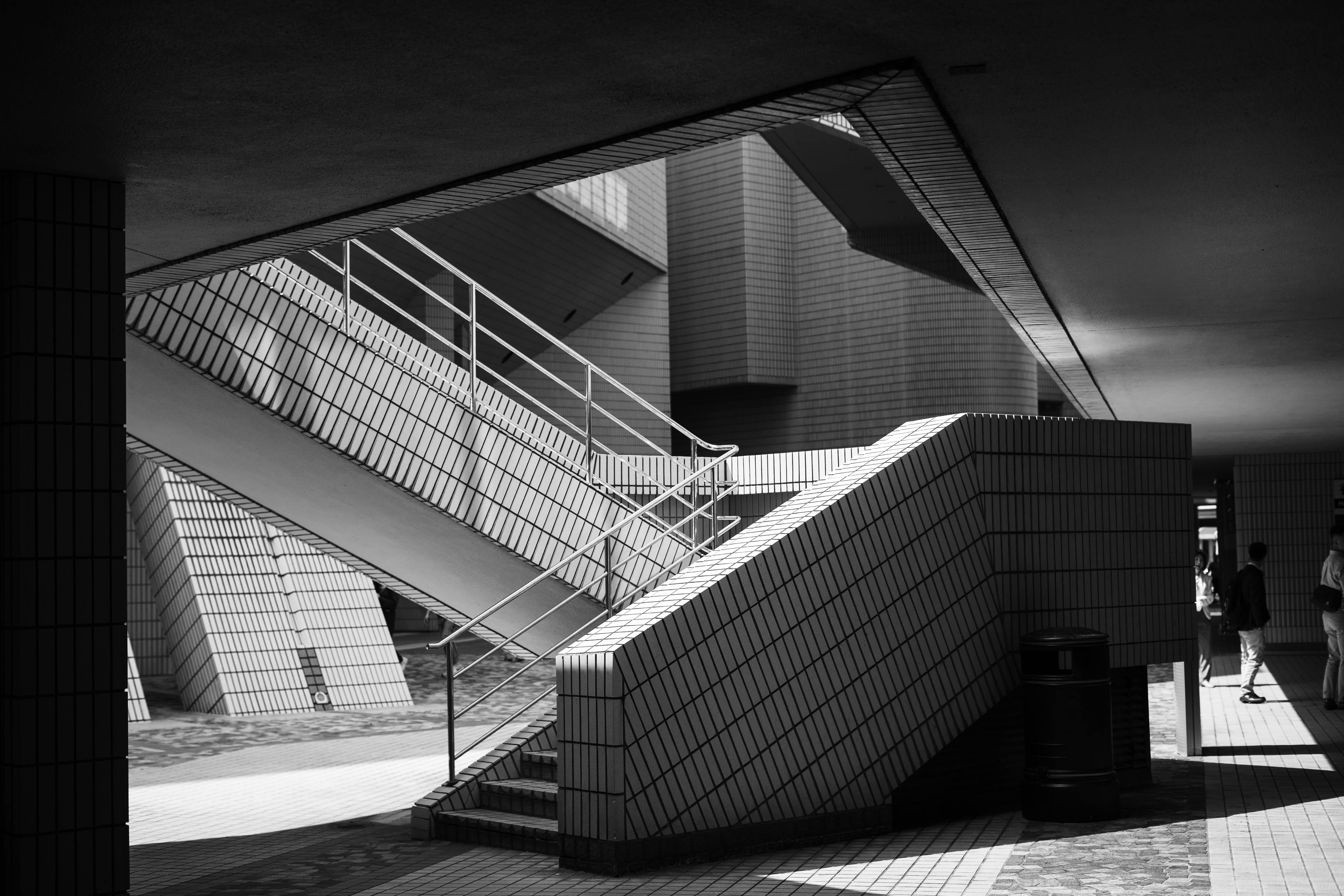 A black and white photograph of a modern architectural staircase in Kowloon, Hong Kong.