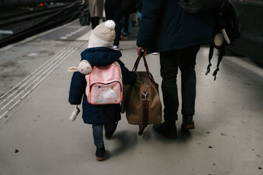 A child and adult carrying bags at a train station platform in Amsterdam.