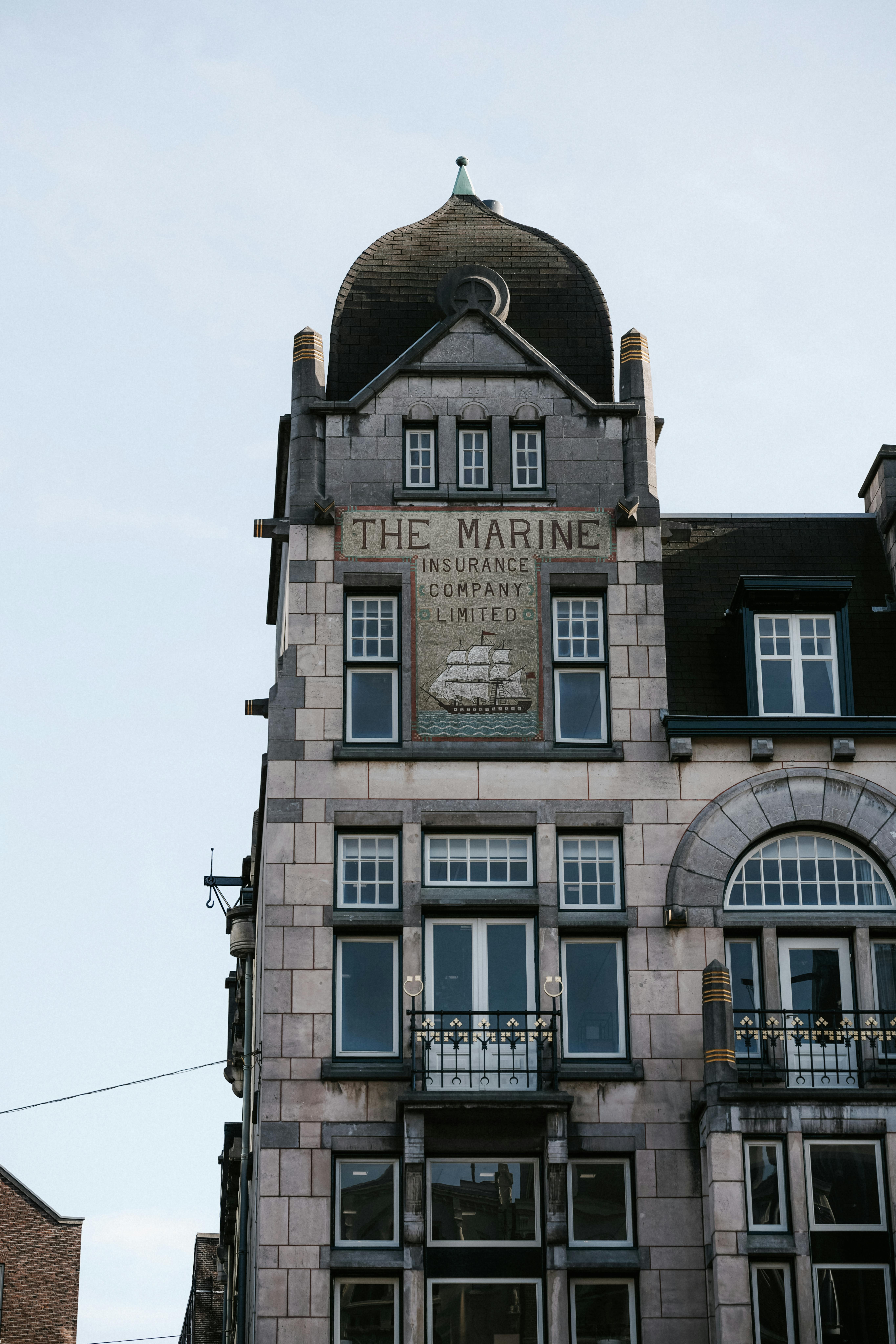 Classic Amsterdam building featuring 'The Marine Insurance Company Limited' signage.