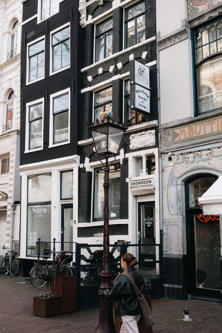 Authentic street view of Amsterdam with iconic architecture and a passerby.