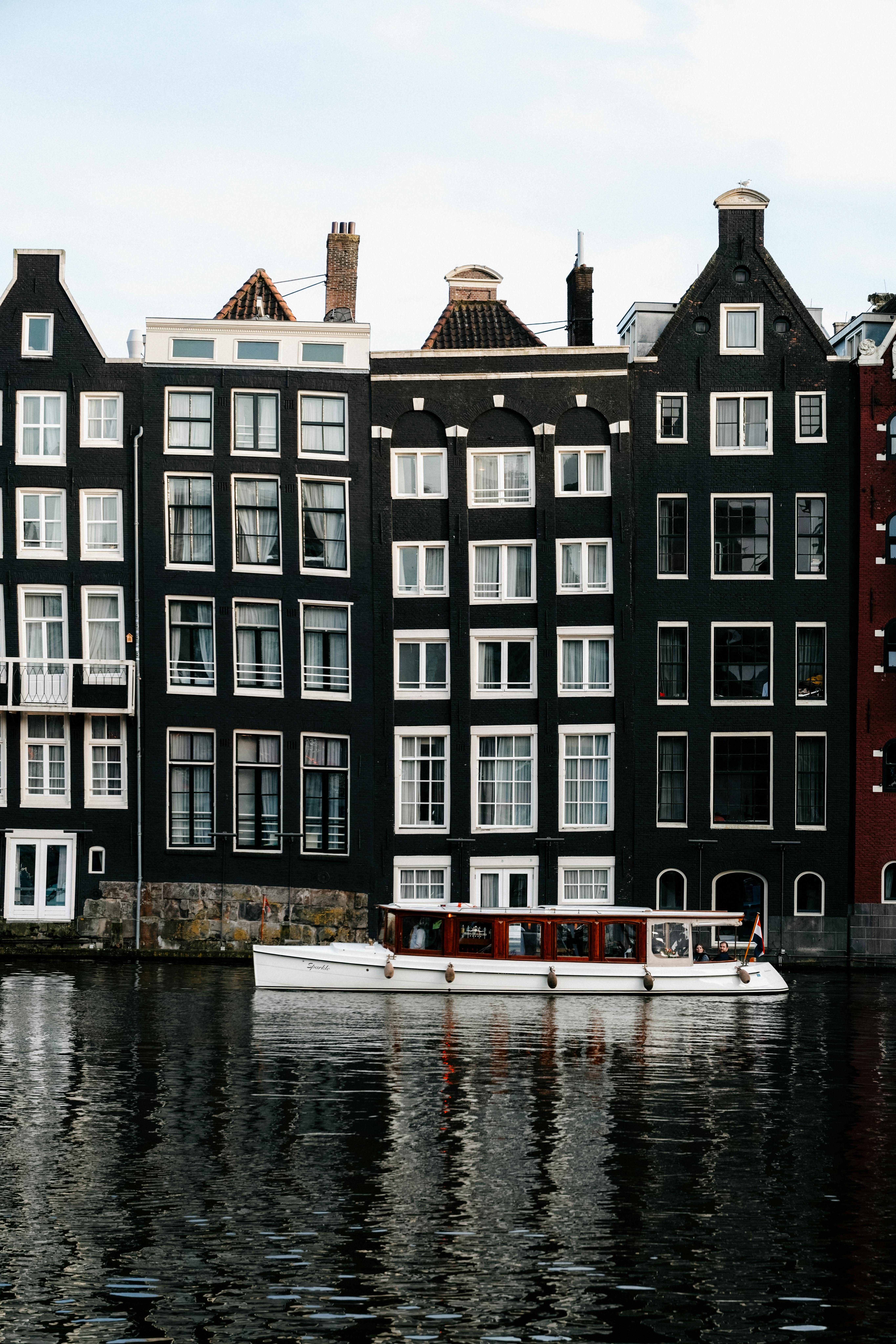 Charming view of Amsterdam's iconic canal houses and a boat on the water, a perfect Dutch scene.