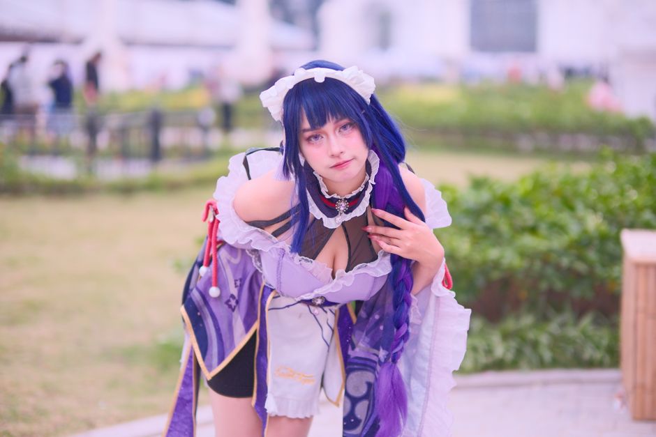 A person in vibrant cosplay costume posing in an outdoor garden area.