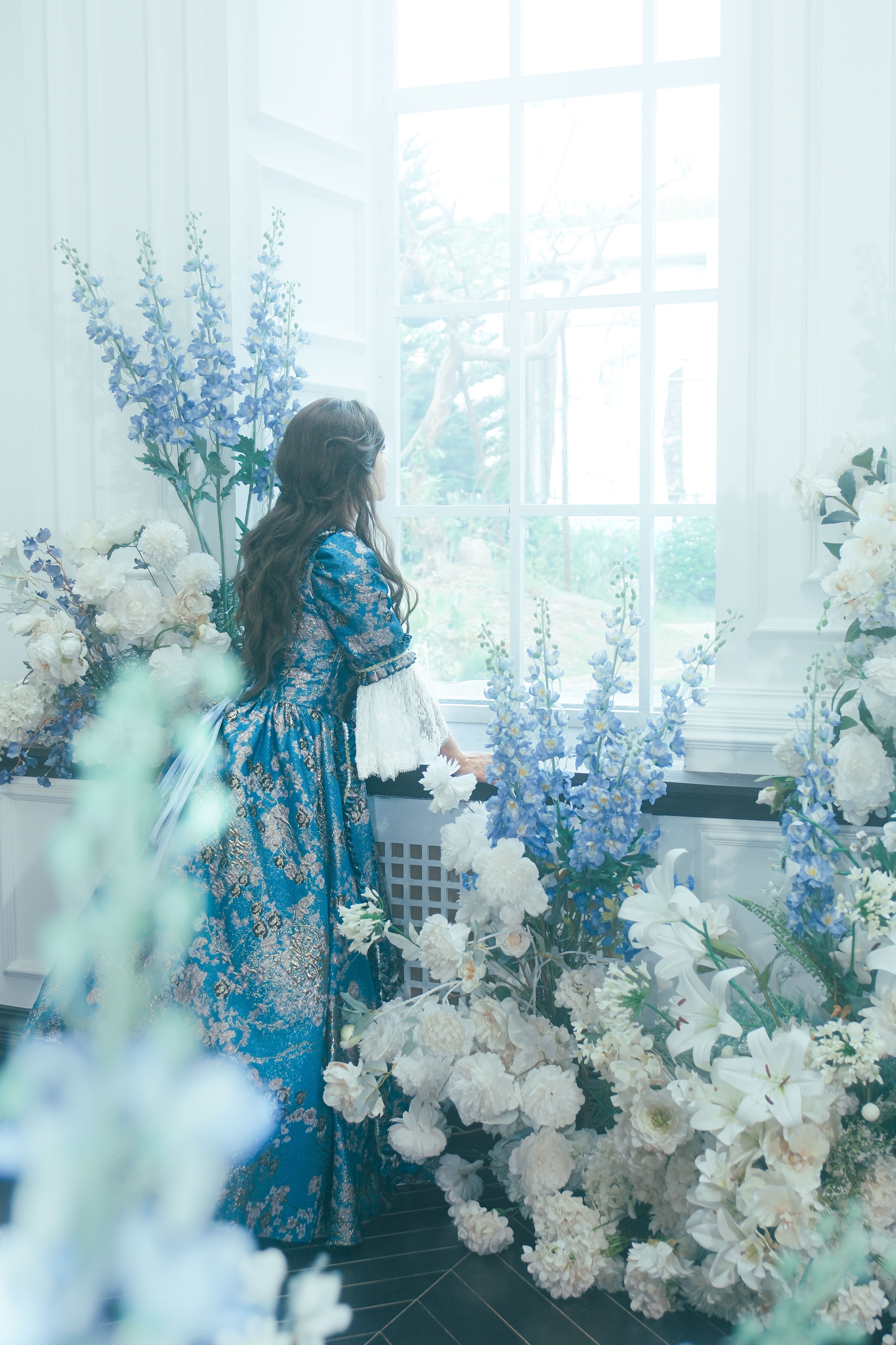 Elegant Woman in Floral Blue Dress by Garden Window · Free Stock Photo