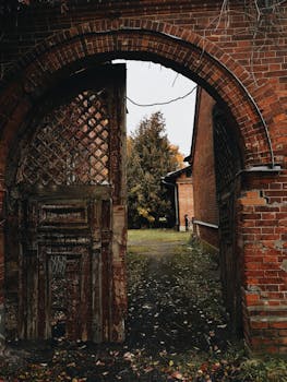 一条砖砌的废弃拱门通向庭院，四周秋叶环绕