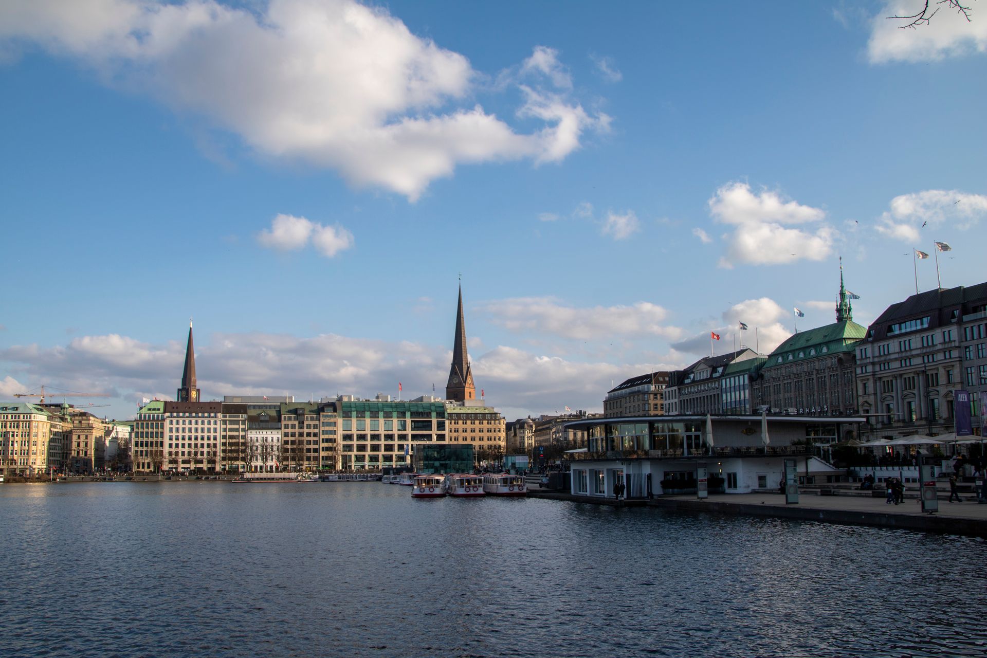 Beautiful view of Hamburg's cityscape featuring Alster Lake under a bright sky.