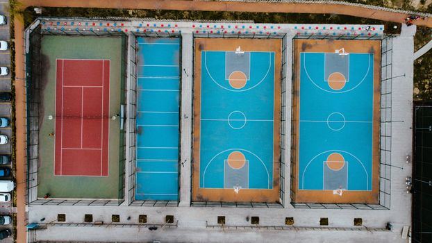 Aerial shot capturing tennis and basketball courts in a city park setting.