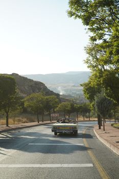 Sunny drive in a vintage convertible on a winding mountain road.