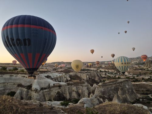Free A stunning view of colorful hot air balloons floating over the rocky landscape of Cappadocia at sunrise. Stock Photo