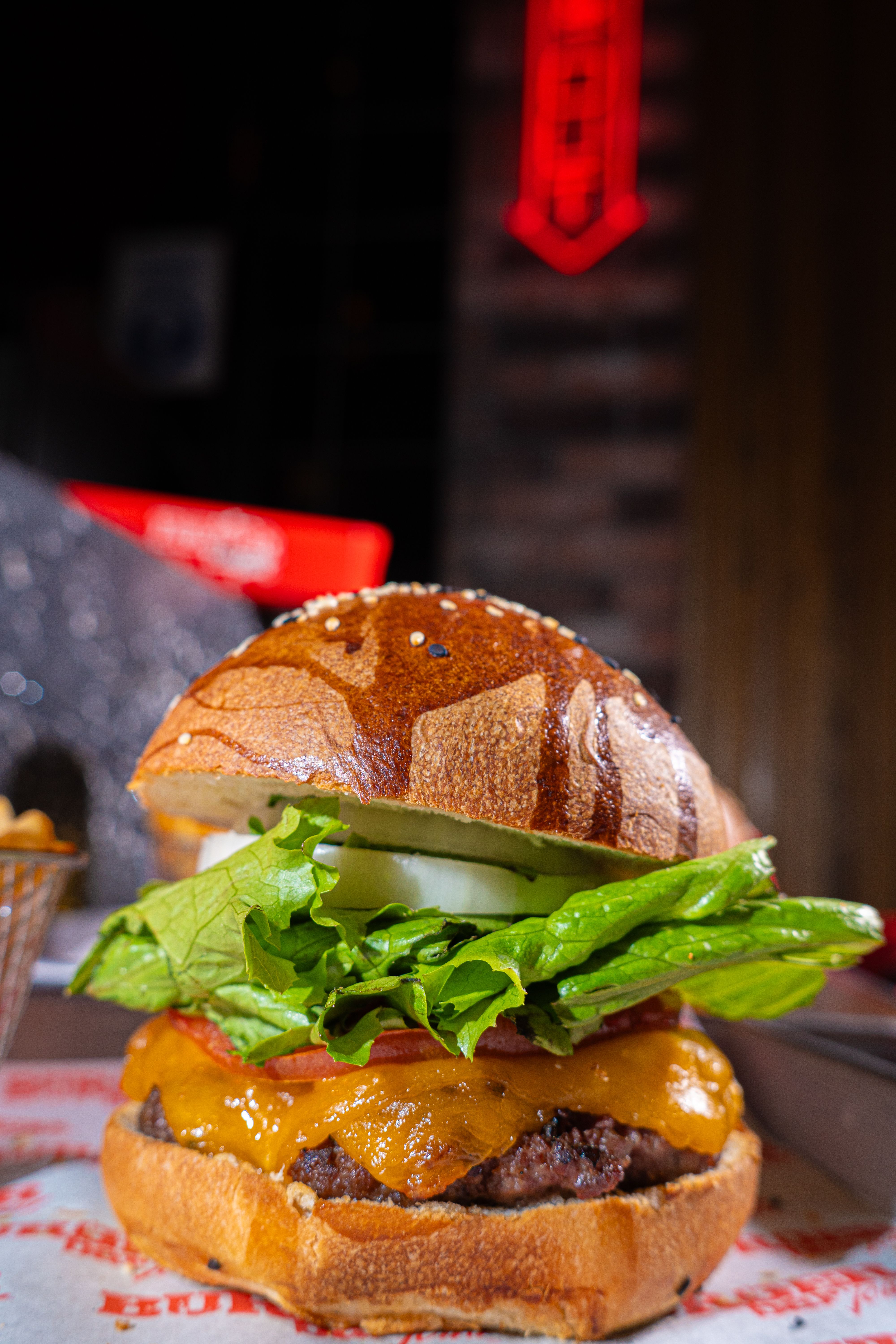Close-up of a delicious cheeseburger with fresh ingredients on a rustic table.