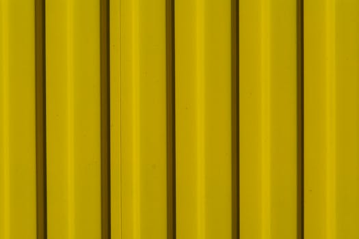 Close-up of a vibrant yellow corrugated metal surface for industrial backgrounds.