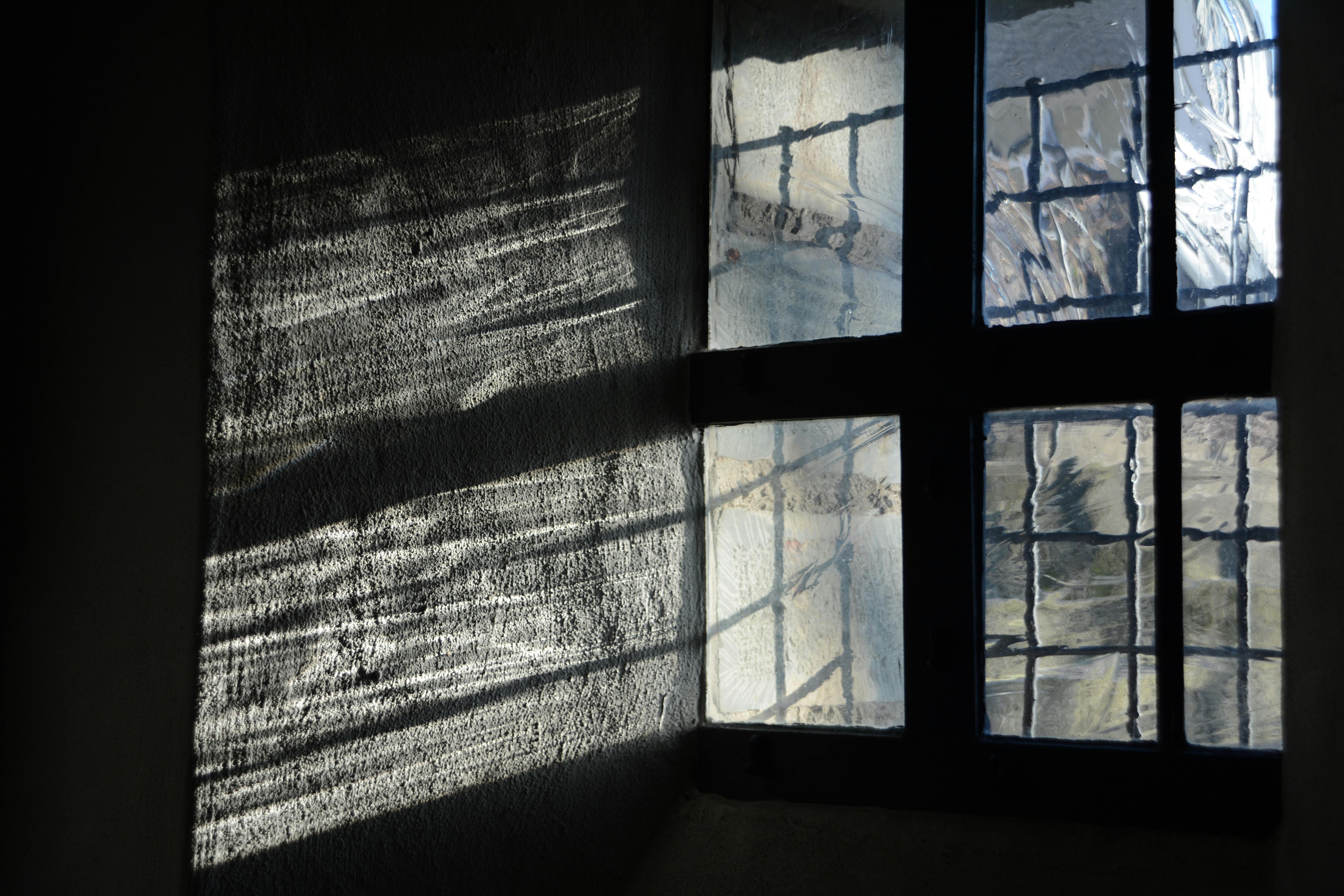 Sunlight creating patterns through an old textured window in a historic building.