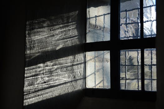 Sunlight creating patterns through an old textured window in a historic building.