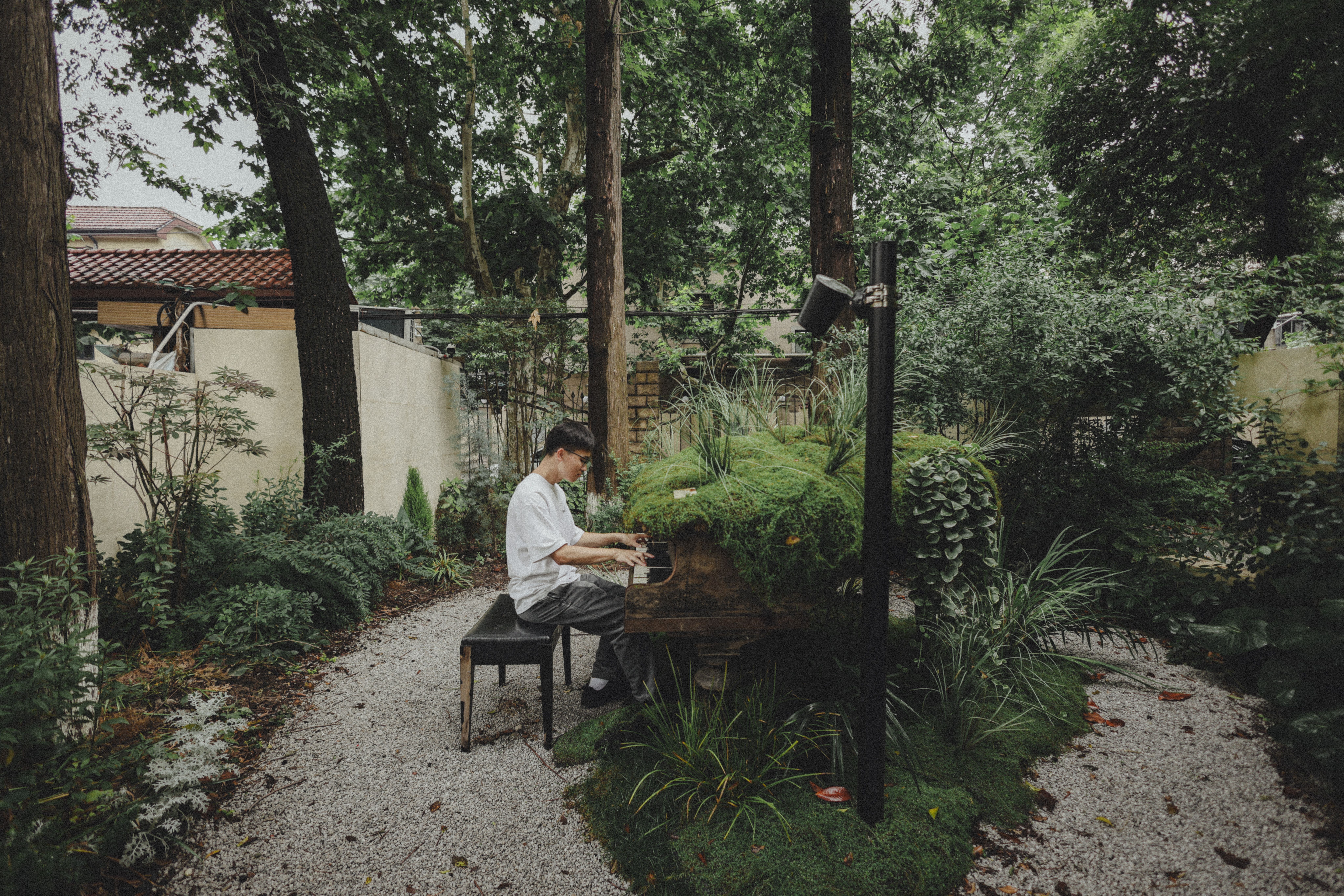 A peaceful moment as a man plays piano amidst lush greenery in Shanghai, China.