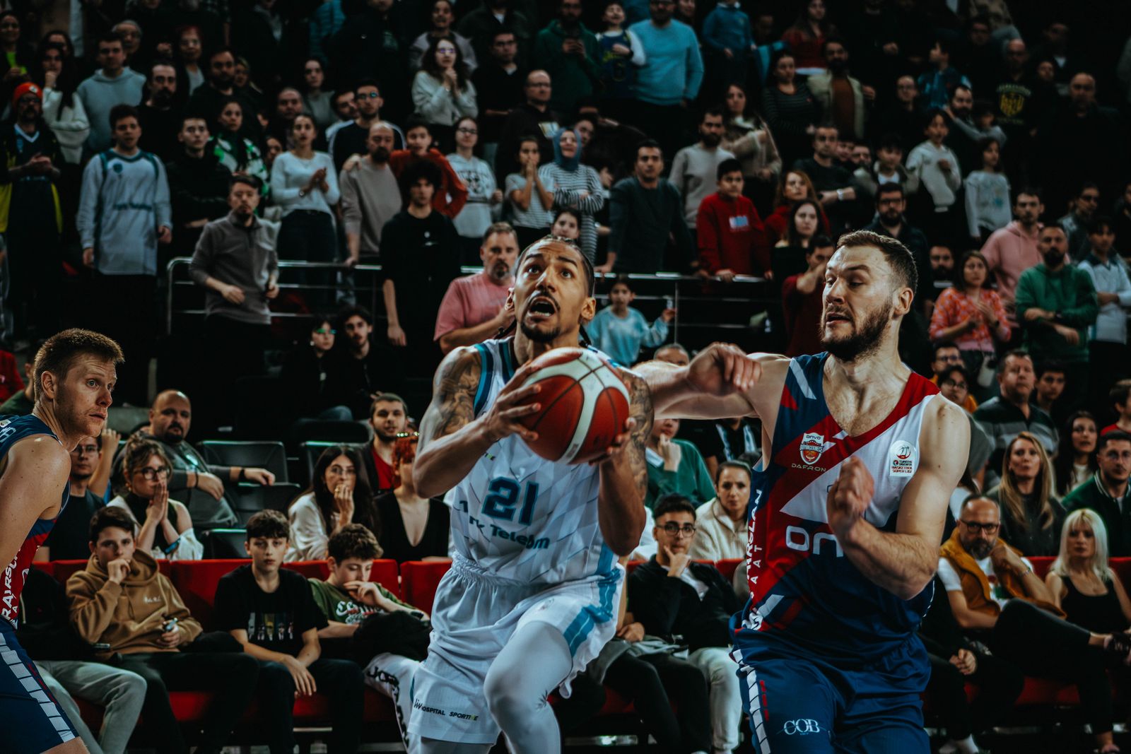 Azione di gioco durante una partita di basket con il pubblico sugli spalti dell’arena