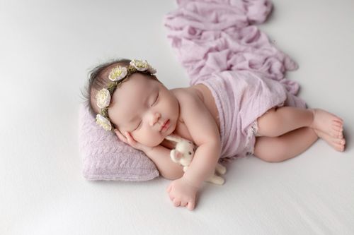 Free Peaceful newborn baby sleeping with floral headband and soft blanket. Stock Photo
