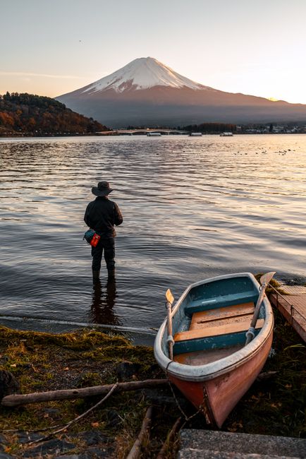 A fisherman stands at Lake Kawaguchi, Yamanashi, with Mount Fuji in the background during sunset.