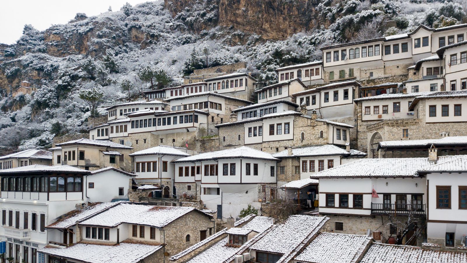 Ottoman-era stone houses on an Albanian hillside dusted with snow after a rare winter snowfall