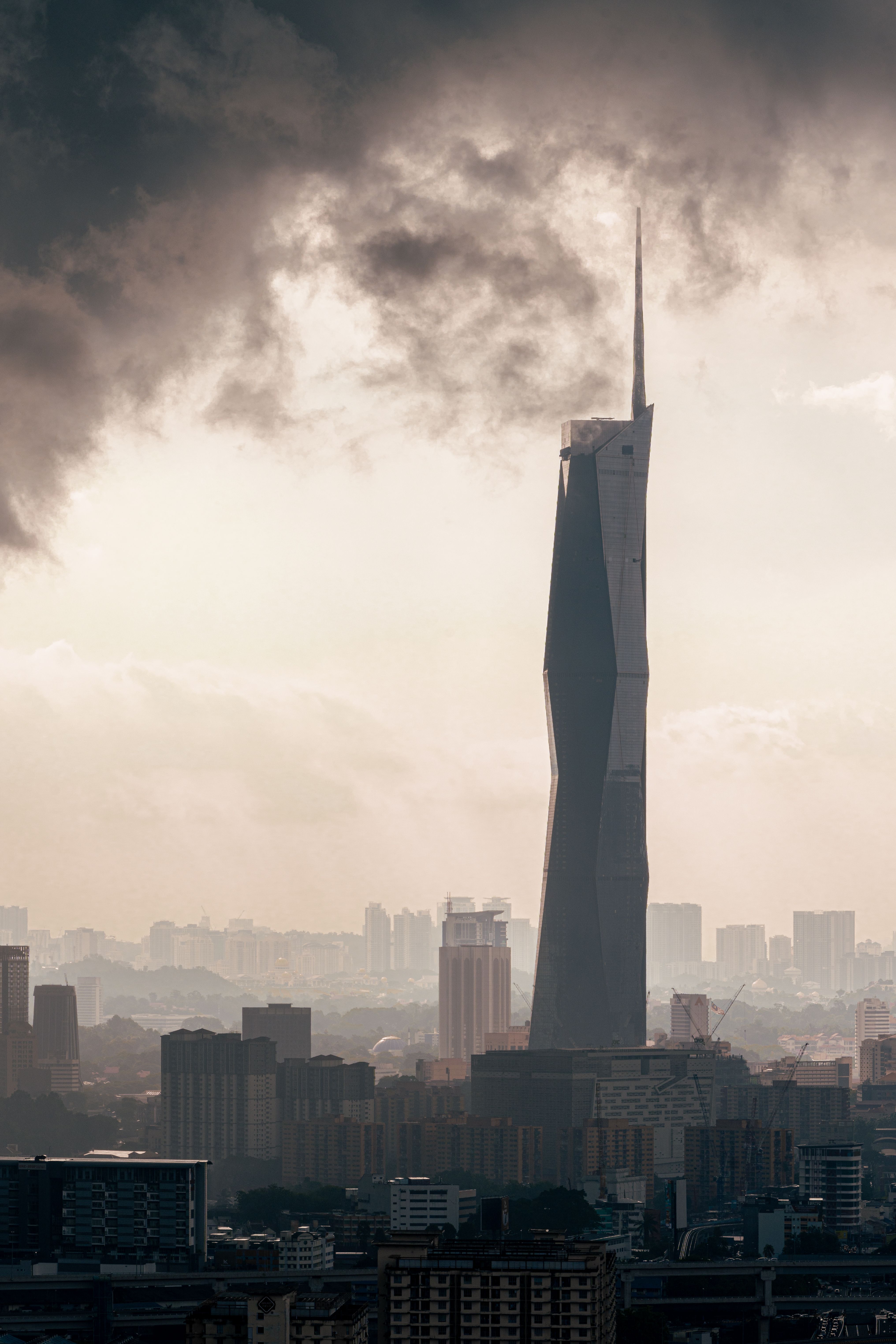 View of Merdeka 118 tower amidst Kuala Lumpur skyline under dramatic skies.