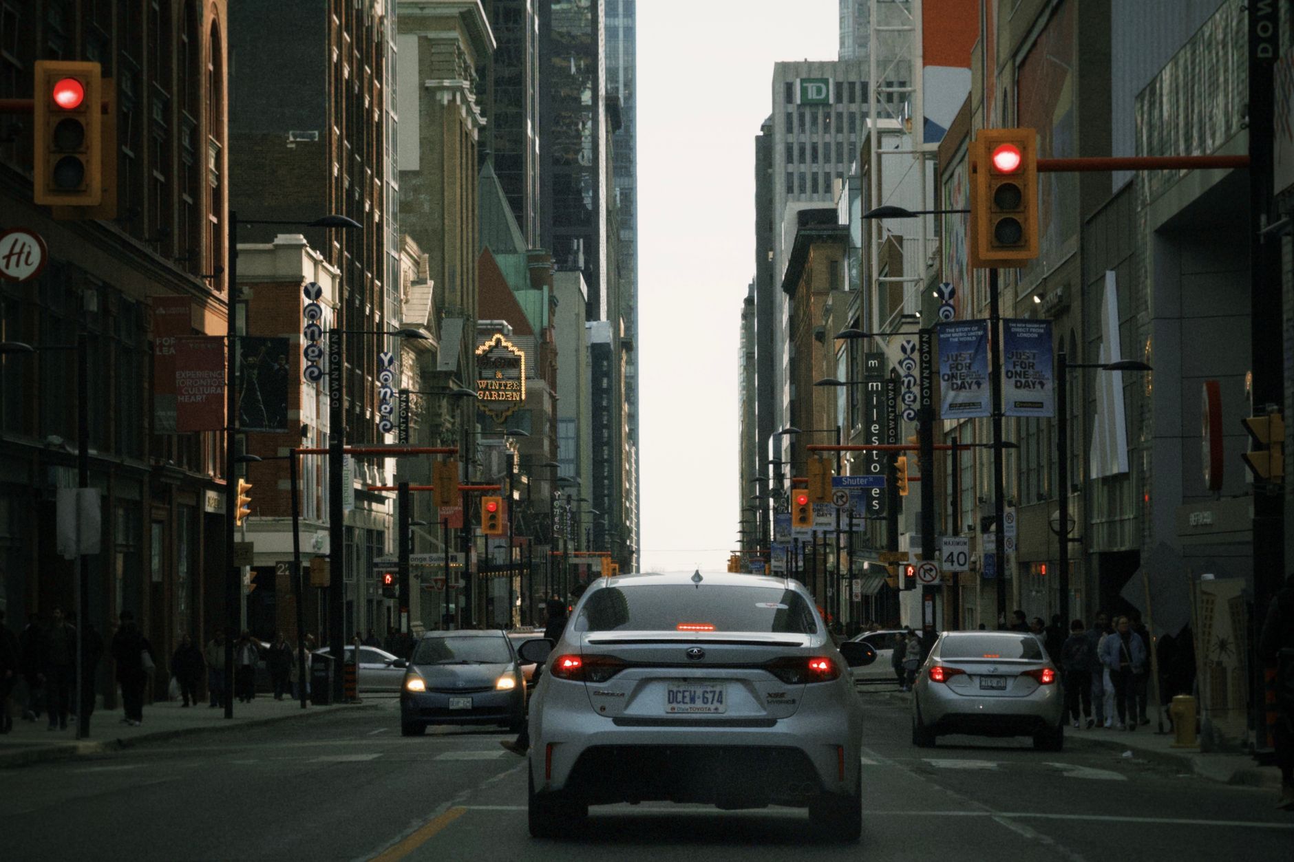A bustling street view of downtown Toronto with cars and urban buildings in the background.