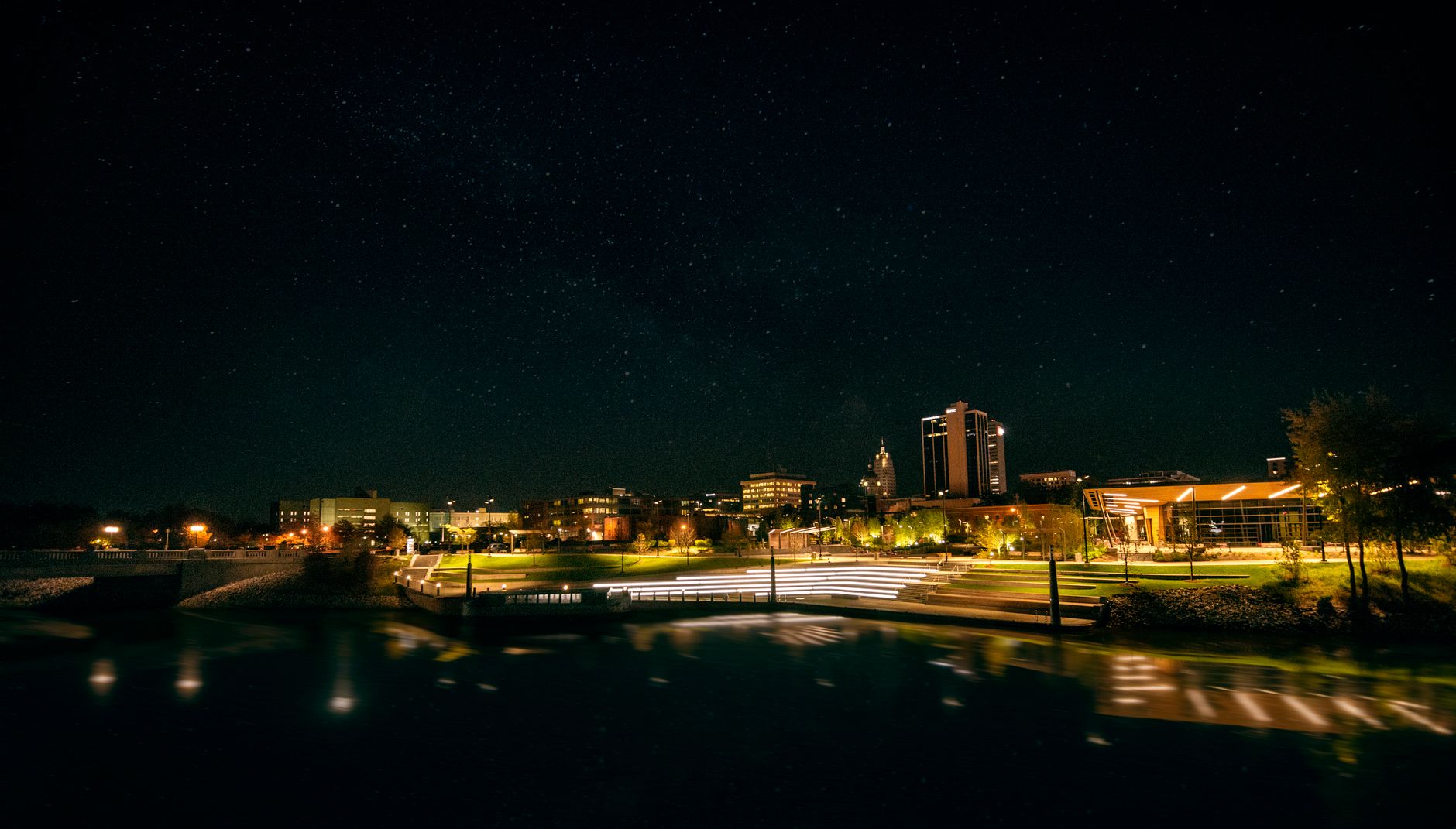 Captivating night view of Fort Wayne skyline with illuminated city lights and clear starry sky.