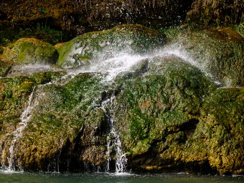 Free A serene waterfall cascades over moss-covered rocks, creating a peaceful natural scene. Stock Photo
