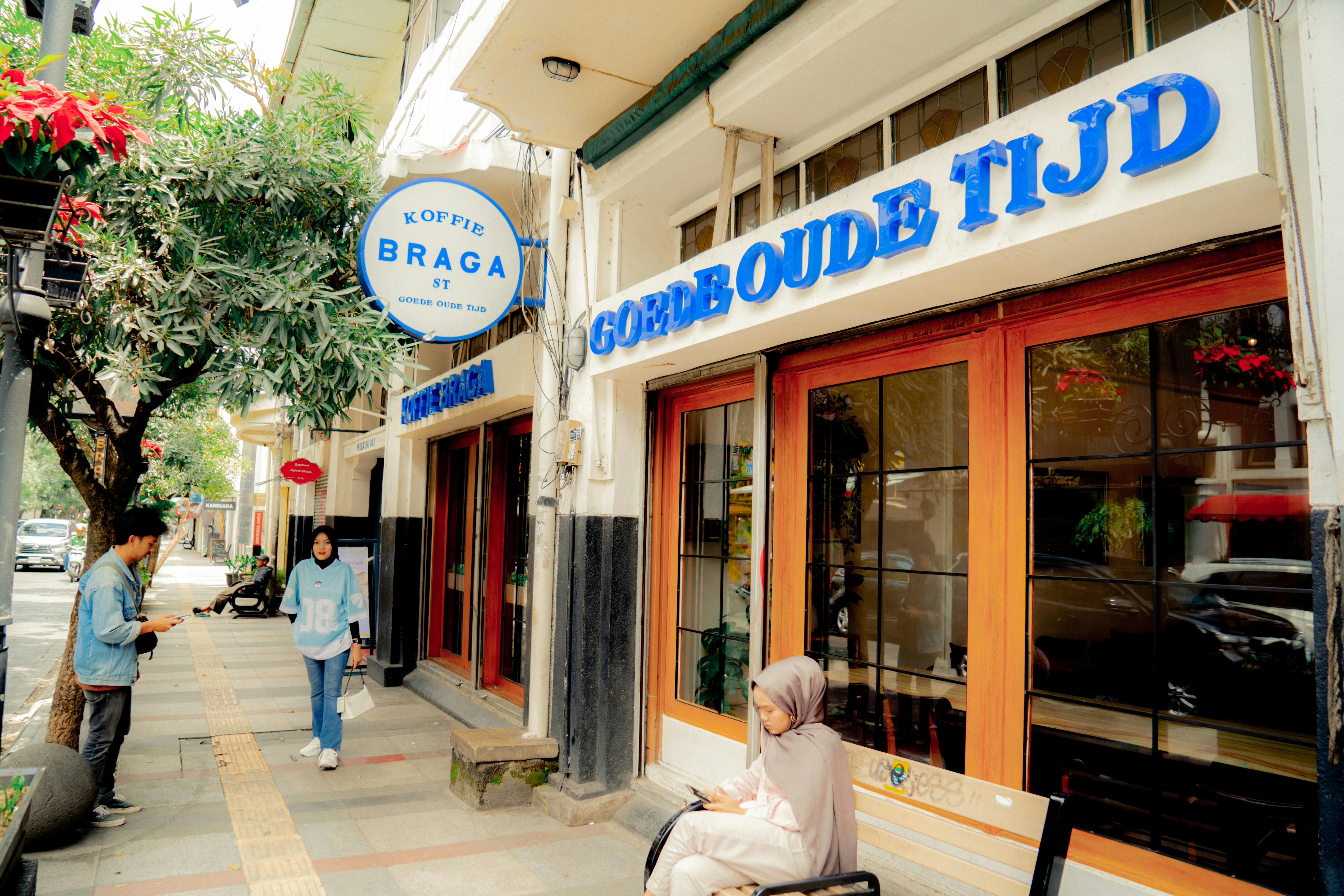Colorful cafe facade on Braga Street, Bandung, Indonesia with people enjoying the outdoor setting.