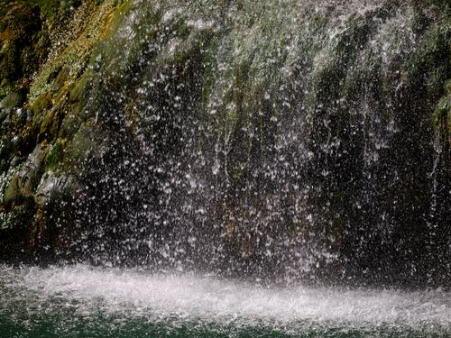 Free A serene waterfall cascading onto mossy rocks, creating a misty ambiance. Stock Photo