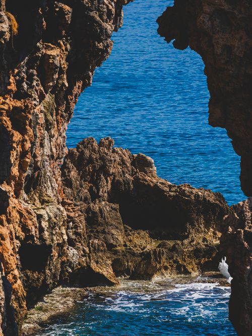 Free A breathtaking view of the ocean framed by rugged coastal cliffs and a clear blue sky. Stock Photo