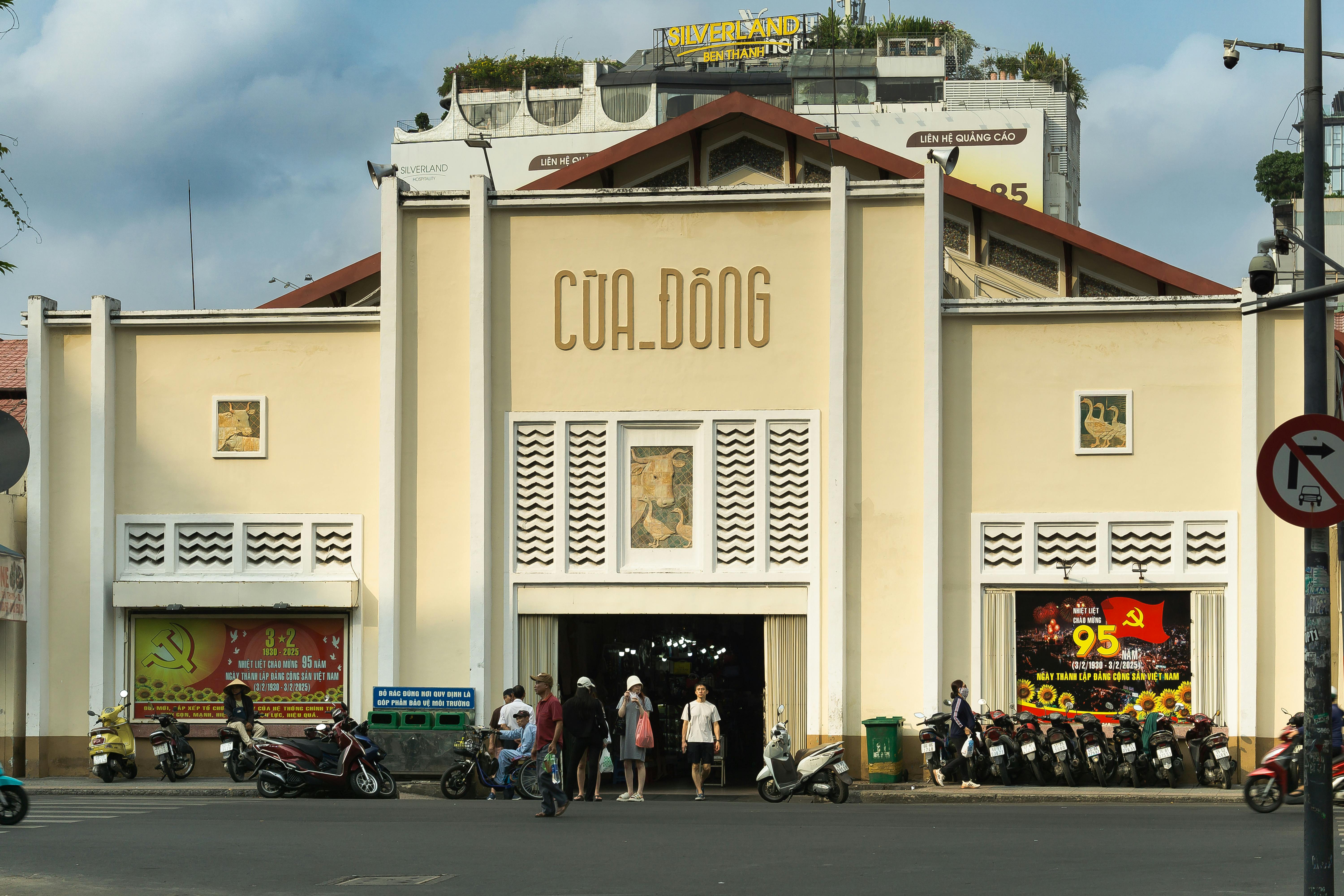 Exterior view of Cua Dong market with people and motorbikes in Ho Chi Minh City.